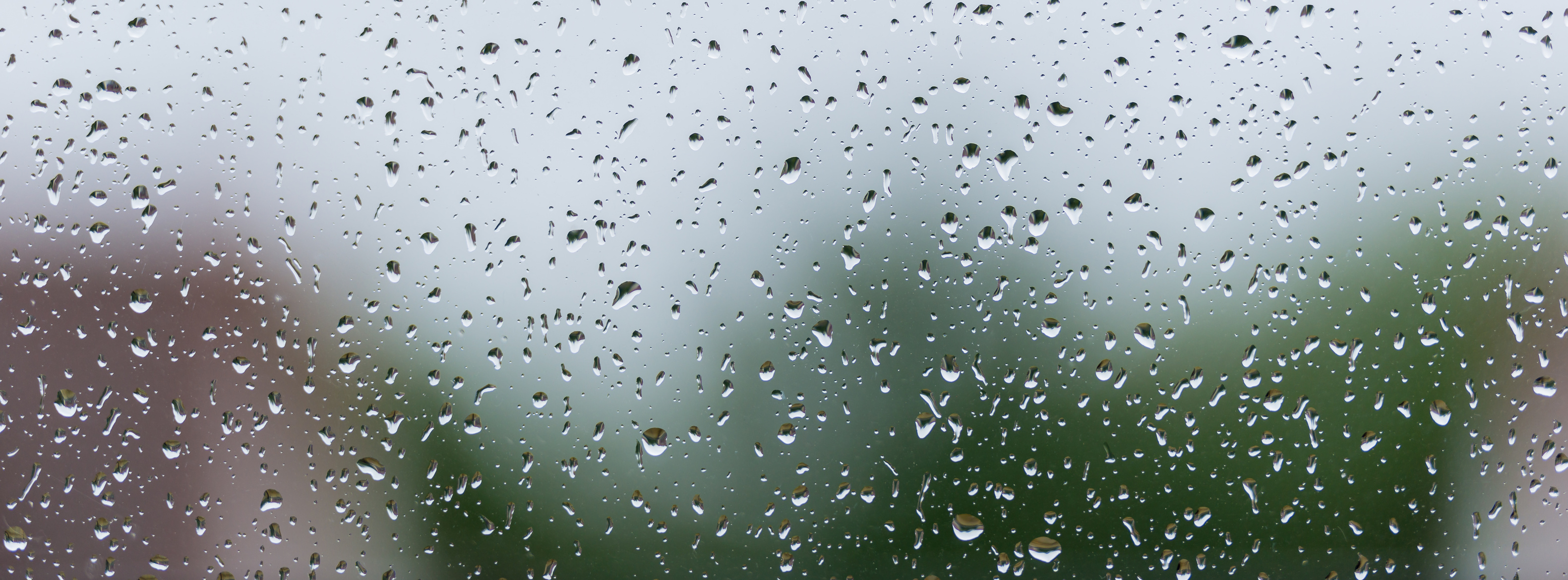 Regentropfen an Glasscheibe Starkregen draußen - Starkregenprävention